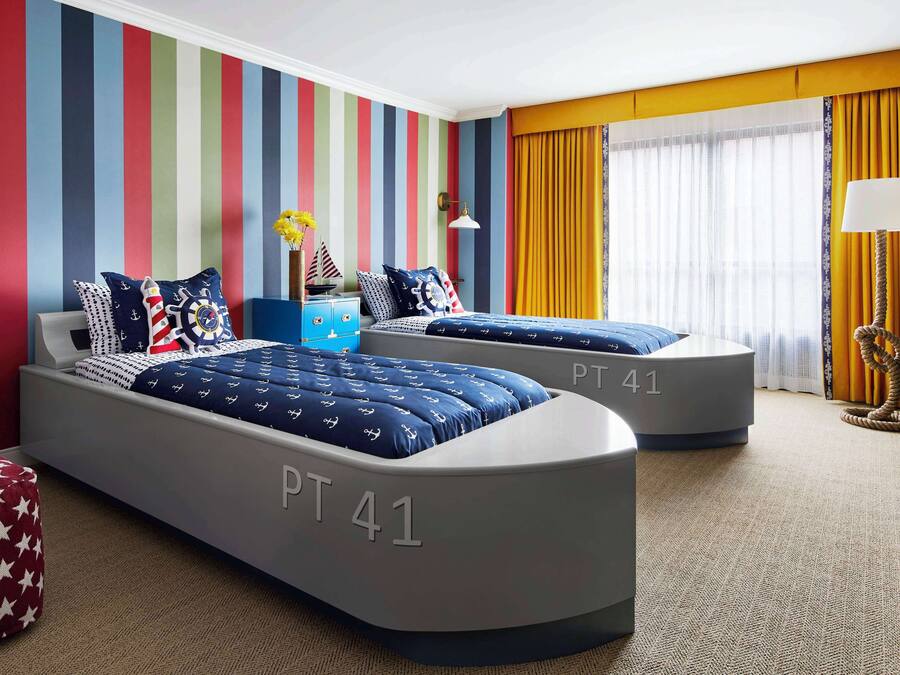 A hotel room with two beds labeled PT 41, striped walls, a small desk, and a window with curtains.