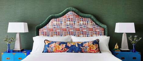 A bed with a patterned headboard, two bedside tables with lamps, and a blue nightstand.
