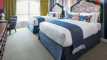 A hotel room with two beds, a desk, a chair, and a window with curtains.