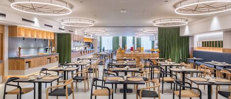 Un restaurant moderne avec des luminaires ronds au plafond, des meubles en bois et un espace de restauration central.