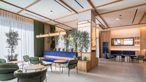 Eine moderne Lobby mit einem blauen Sofa, grünen Sesseln und einem Holzbüro.