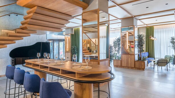Eine moderne Bar mit einer Holztresen, blauen Barhocker und einer Treppe mit Holzstufen.