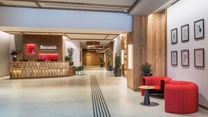 Ein Hotel-Rezeptionsbereich mit einer Rezeption, einem roten Sofa und gerahmten Kunstwerken an der Wand.