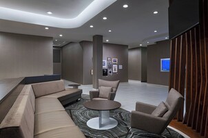 A modern lobby with a curved seating area, a round table, and a television screen.