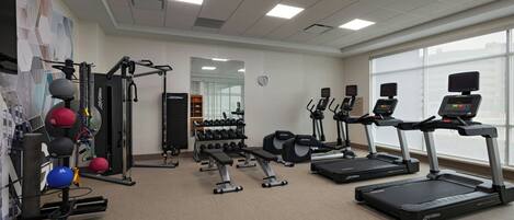 A gym with treadmills, weight machines, and a variety of weights.