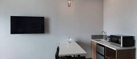 Una cocina compacta con una televisión de pantalla plana, un microondas y un lavavajillas.