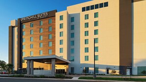 Un hotel moderno con una entrada destacada, varios pisos y cielo despejado.