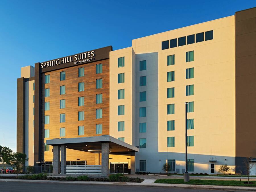 A modern hotel with a prominent entrance, multiple floors, and a clear sky.