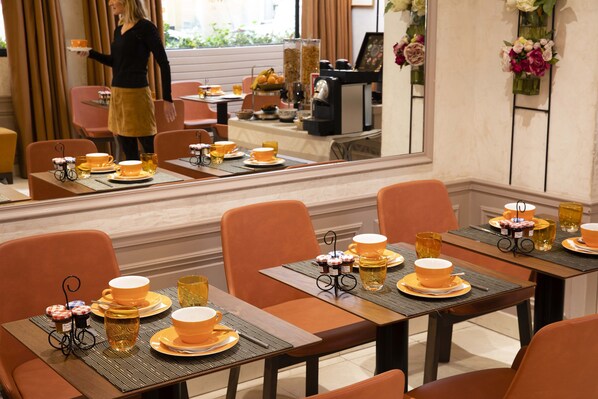Un restaurante con varias mesas dispuestas para comer, cada una con manteles naranjas y vajilla amarilla.