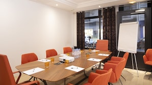 A conference room with a wooden table, orange chairs, a projector, and a whiteboard. - Hotel Vaneau Saint Germain (Paris)