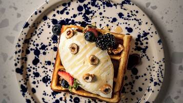 Um prato com um waffle, sorvete e frutas vermelhas.