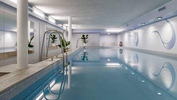 Una piscina interior moderna con agua cristalina, paredes blancas y un diseño minimalista.