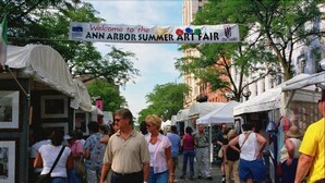 A street lined with market stalls and a banner welcoming to the Ann Arbor Summer Art Fair. - A Victory Inn & Suites - Ann Arbor (Ann Arbor)
