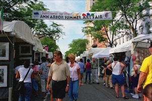 Una calle con un cartel que dice 'Welcome to the Ann Arbor Summer Art Fair'.