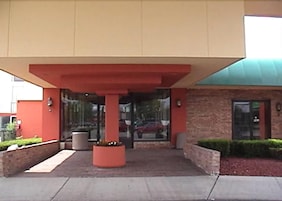Un edificio con fachada roja, amplios ventanales de vidrio y techo verde.