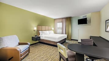A hotel room with a bed, a desk, a chair, a sofa, and a television.