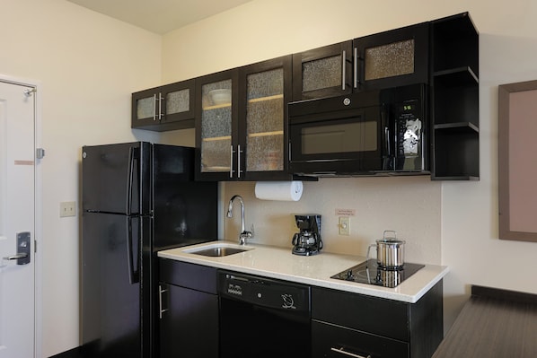 Una cocina compacta equipada con refrigerador, microondas, cafetera y lavavajillas.