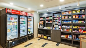 Un espacio para bebidas y aperitivos, con dos refrigeradores, estantes llenos de bocadillos y un microondas.