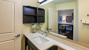 A bathroom with a sink, mirror, and shelves.