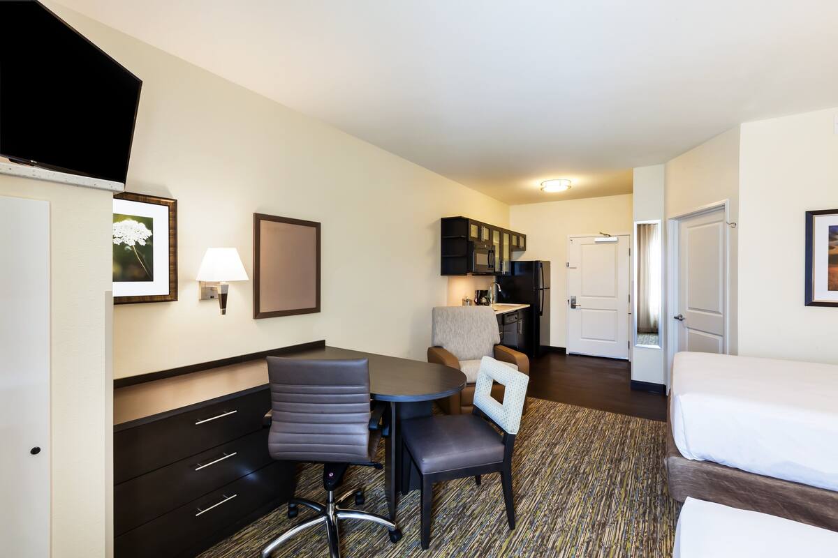 Een hotelkamer met een bed, een bureau met stoel, een klein tafeltje, een bank en een televisie.