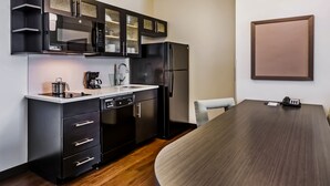 A modern kitchen with black cabinetry, a stainless steel refrigerator, and a built-in oven.
