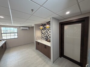 A modern kitchen with a checkered backsplash, a window with a view, and a door with frosted glass.