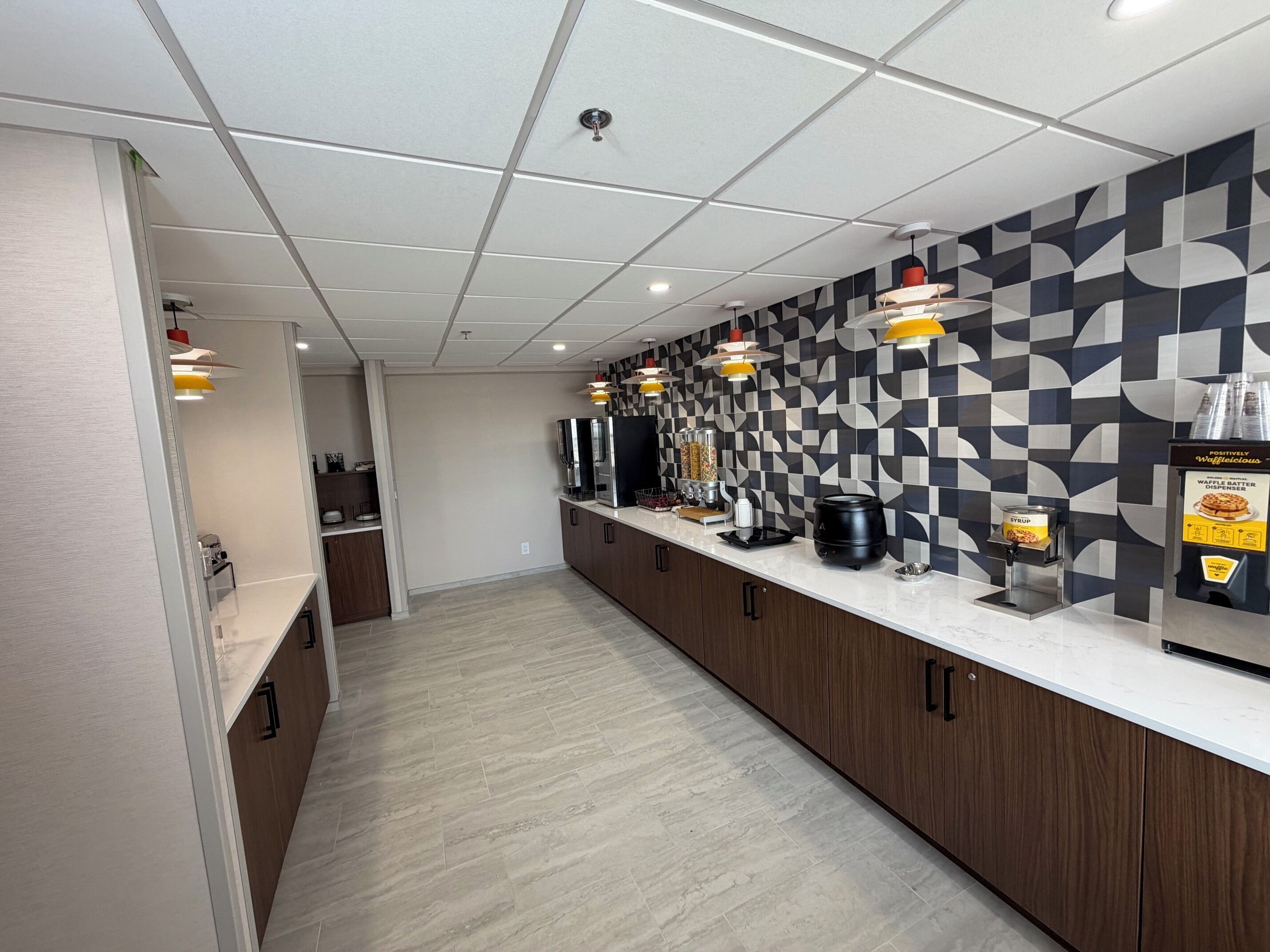 A modern kitchen with a long countertop, built-in appliances, and a patterned backsplash.