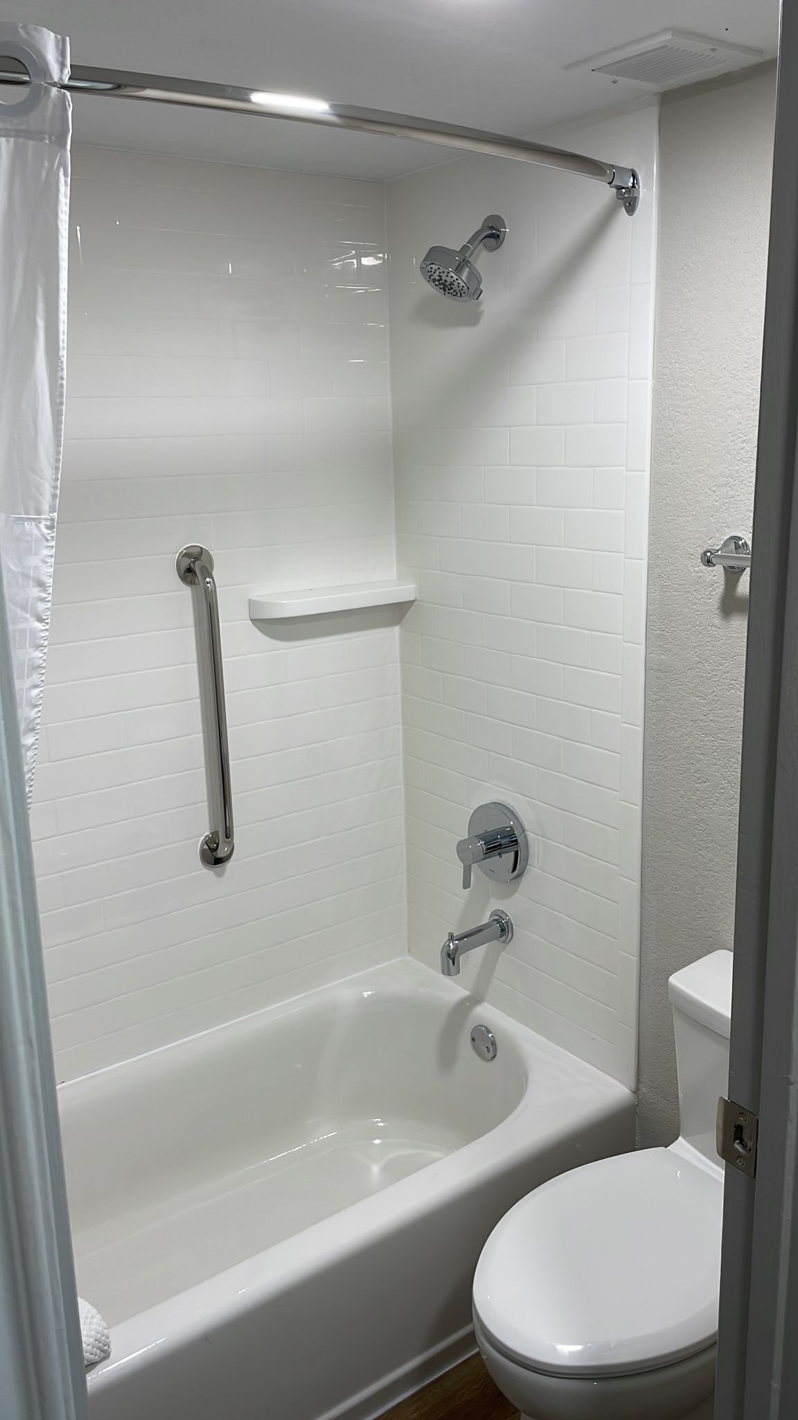Un baño con bañera blanca, inodoro y zona de ducha.