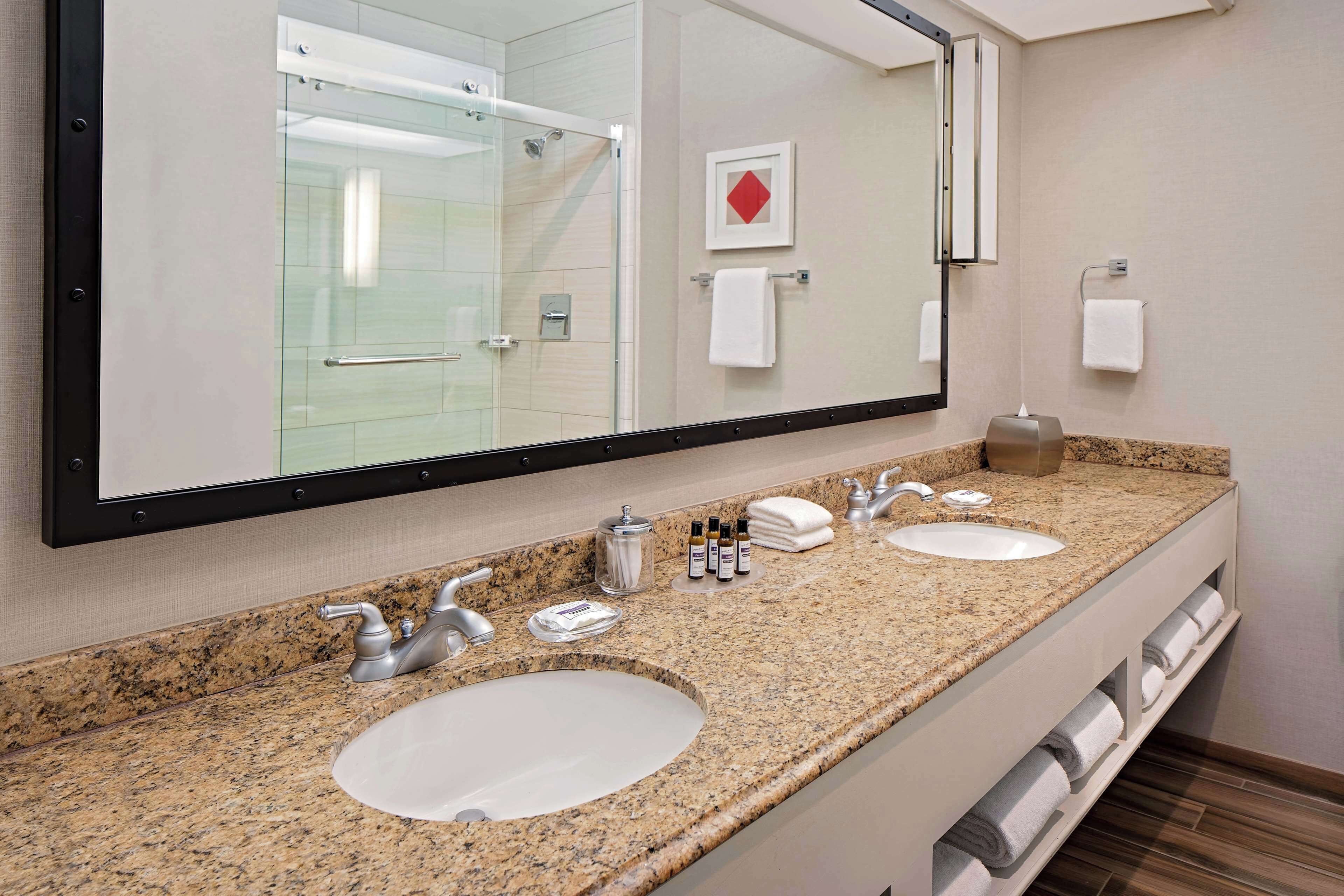 A bathroom with two sinks, a large mirror, and a towel rack.