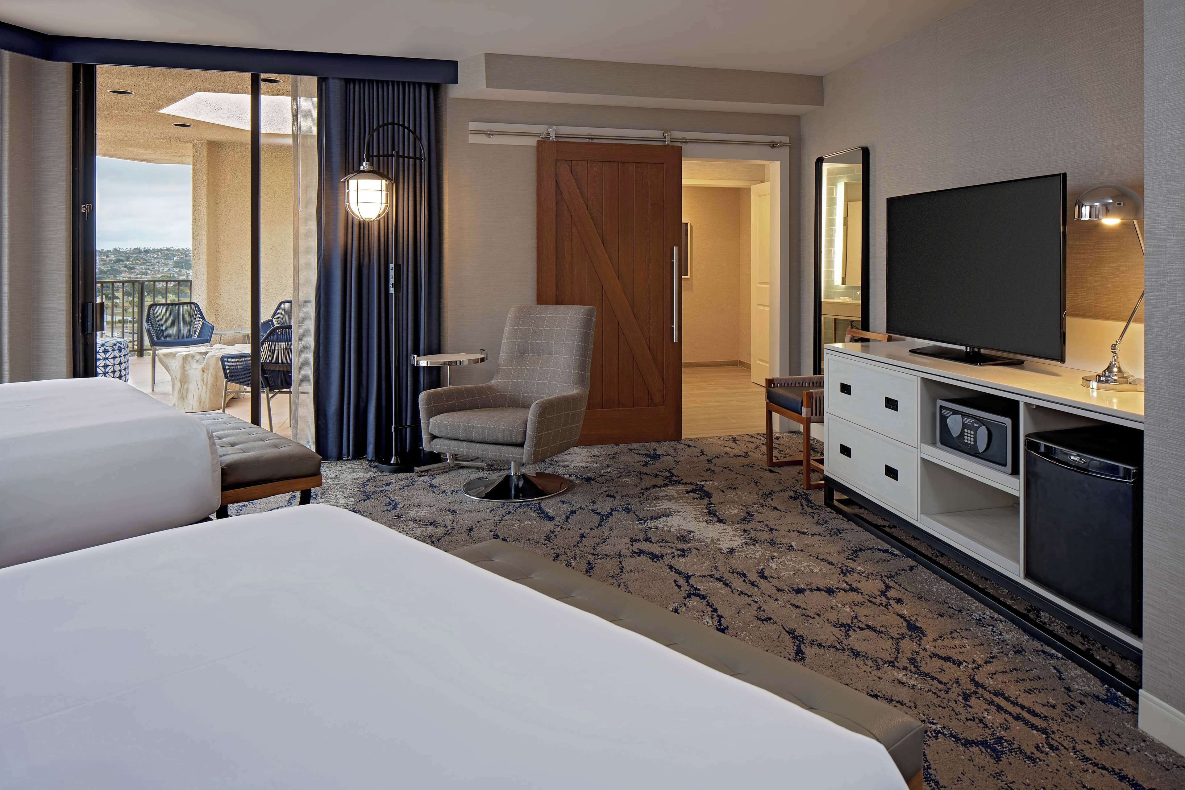A hotel room with two beds, a TV, a desk, and a chair.