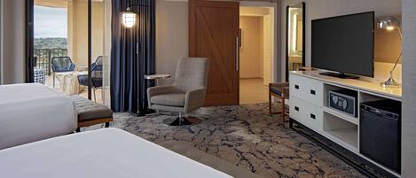 A hotel room with two beds, a TV, a desk, and a chair.