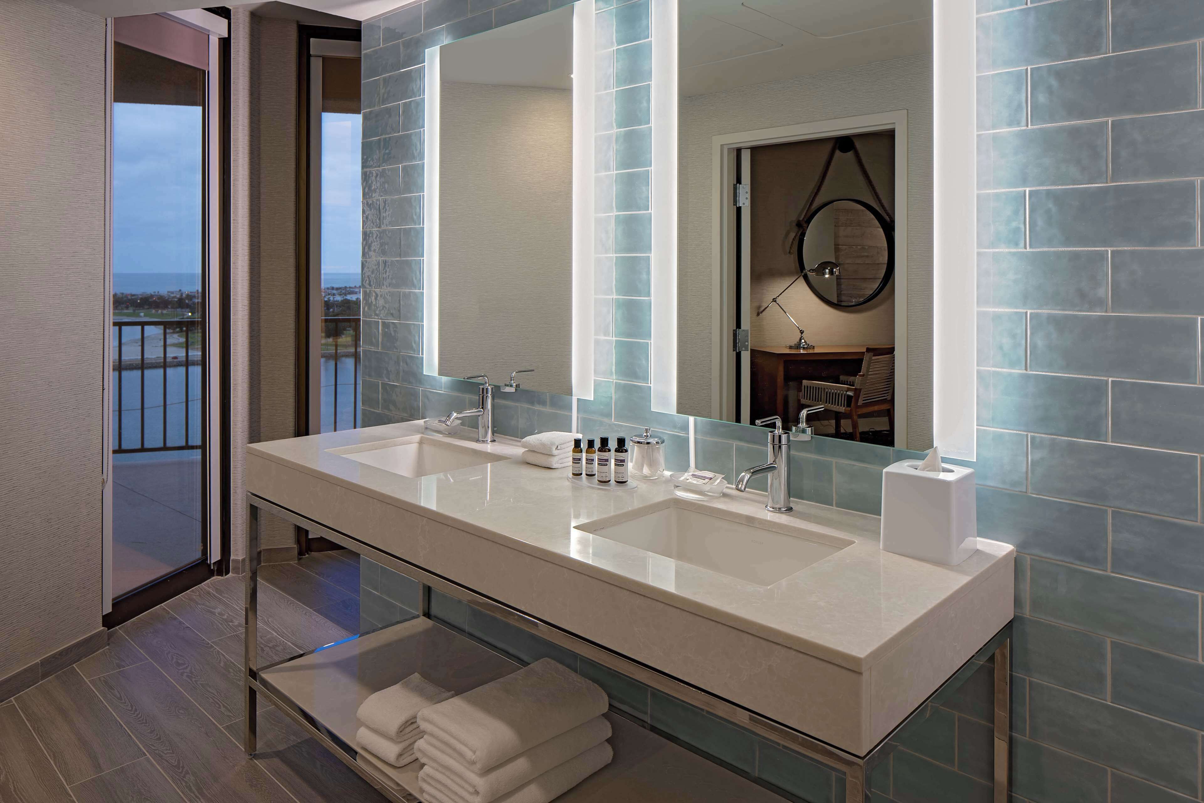 Une salle de bain moderne avec un meuble-lavabo à deux vasques, un grand miroir et une vue sur le balcon.