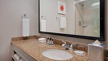 Une salle de bain avec un comptoir en granit, un lavabo, un miroir et un porte-serviettes.