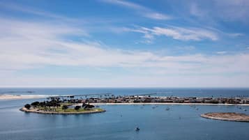 A coastal cityscape with a marina, boats, and a pier extending into the water.