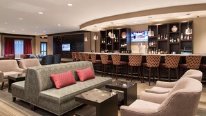 A hotel lobby with a bar area, seating arrangements, and a television screen. - DoubleTree by Hilton Schenectady Downtown (Schenectady)