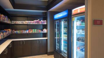 Un angolo cottura con frigorifero Pepsi, ripiani per snack e insegna dello shop della suite.