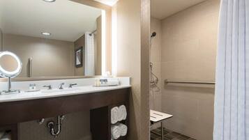 Un baño moderno con tocador, espejo y ducha.