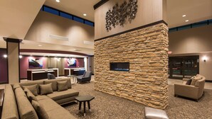 A spacious lobby with a stone accent wall, a large sofa, and a television screen. - DoubleTree by Hilton Schenectady Downtown (Schenectady)