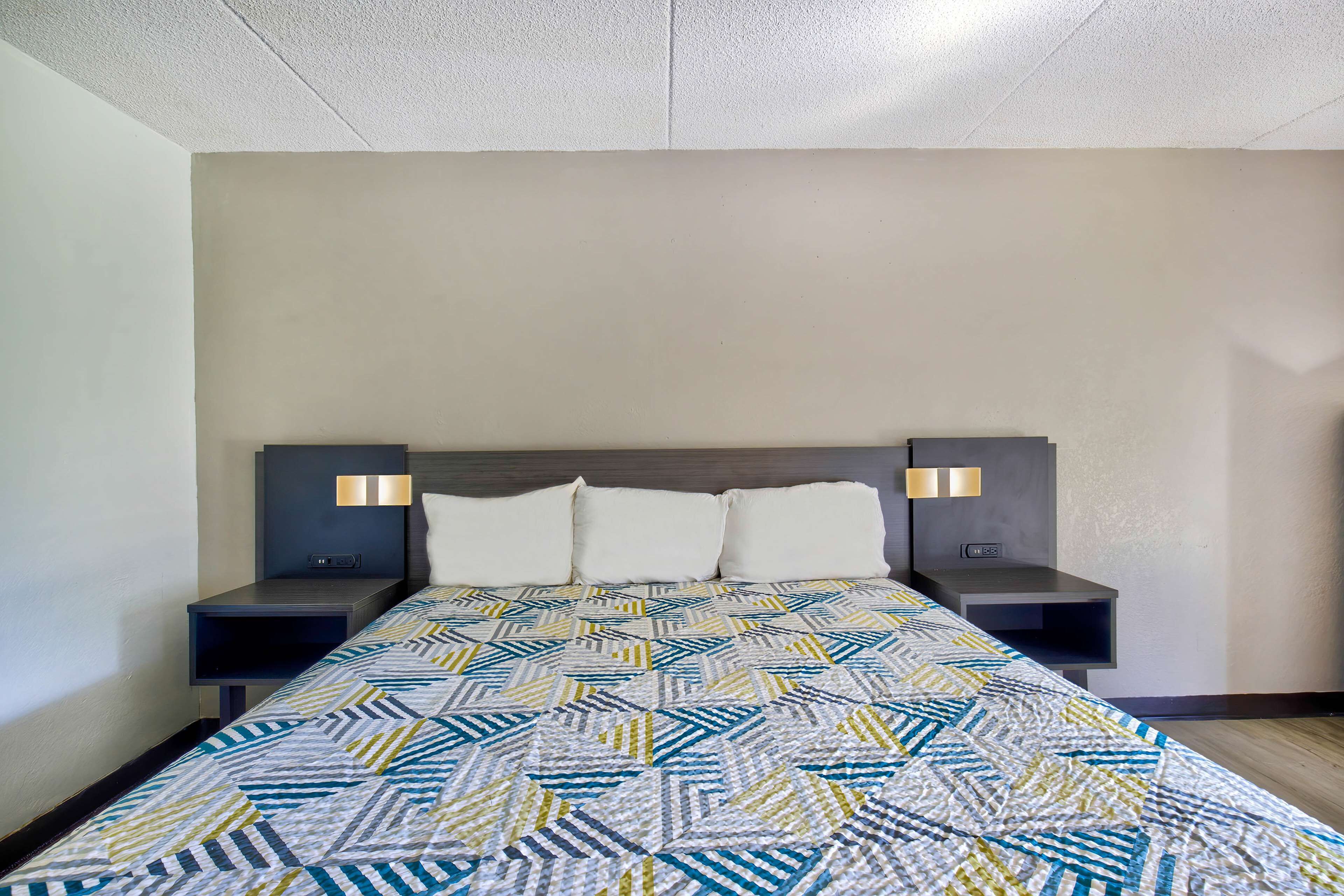 Ein Hotelzimmer mit einem Bett, zwei Nachttischen und einem Kopfteil.
