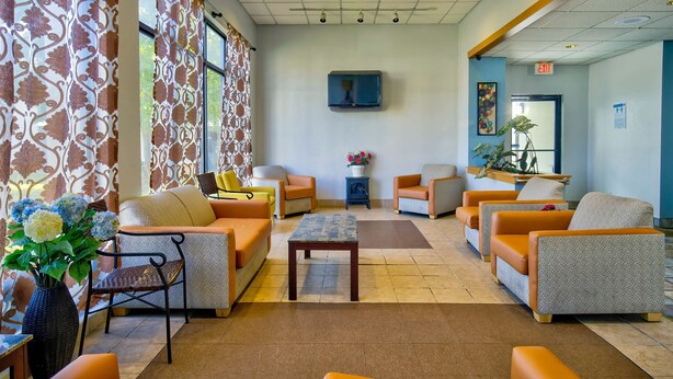 A lobby with sofas, a coffee table, and a vase with flowers. - Motel 6 Ashland, VA (Ashland)