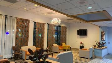 A hotel lobby with a chandelier, seating area, and a television mounted on the wall.