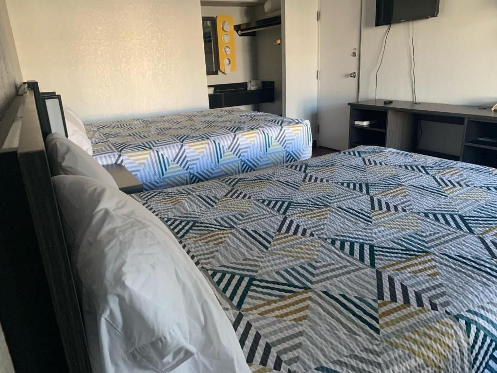 Hotellihuone, jossa on kaksi sänkyä, työpöytä ja televisio.