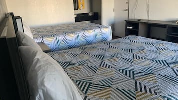Hotellihuone, jossa on kaksi sänkyä, työpöytä ja televisio.