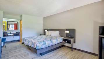 A modern bedroom with a bed, bedside tables, a desk, and a mirror.