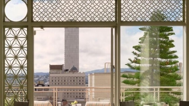 A balcony with a view of a tall building, a tree, and a table with chairs. -  The Huntington Hotel (San Francisco)