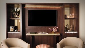 A modern living room with two armchairs, a coffee table, a flat-screen TV, a bookshelf, and a small side table with a vase. -  The Huntington Hotel (San Francisco)
