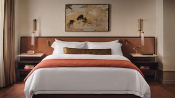 A hotel room with a large bed, two bedside tables, a painting on the wall, and a patterned carpet.