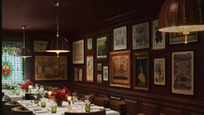 A restaurant with multiple tables set for dining, framed artwork on the walls, and hanging pendant lights. -  The Huntington Hotel (San Francisco)