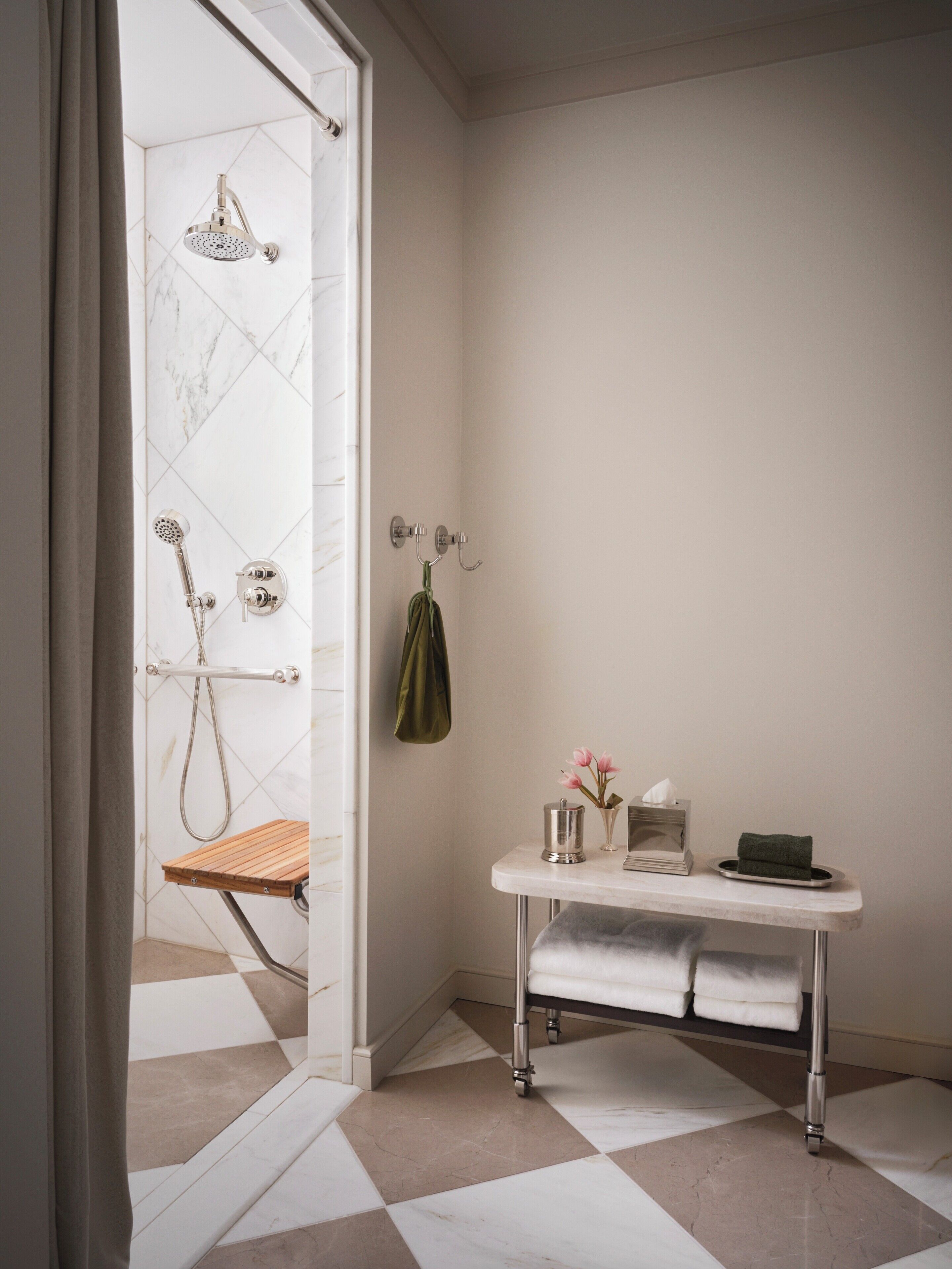 A bathroom with a shower, a towel rack, a small table with toiletries, and a checkered floor.