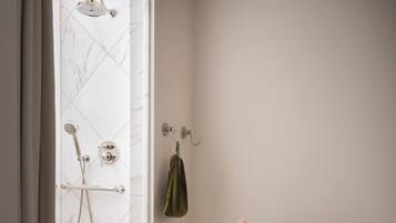 A bathroom with a shower, a towel rack, a small table with toiletries, and a checkered floor.